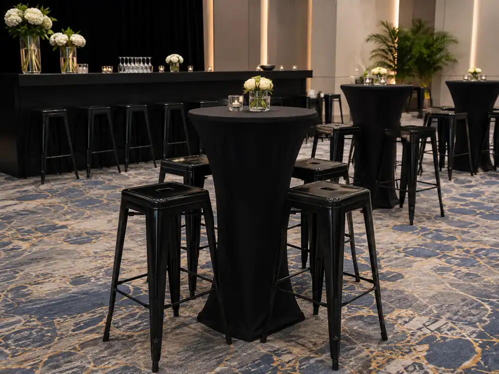 Black Tolix bar stools around black cocktail tables on a patterned ballroom carpet