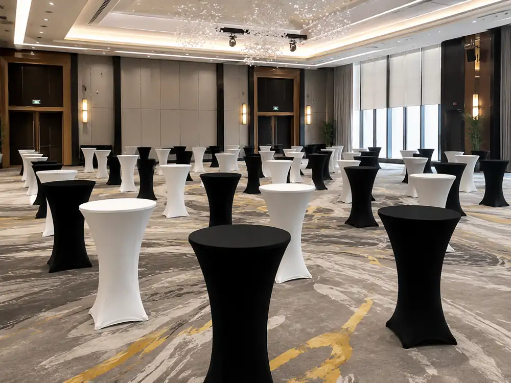 Black and white cocktail tables arranged in a bright ballroom reception space