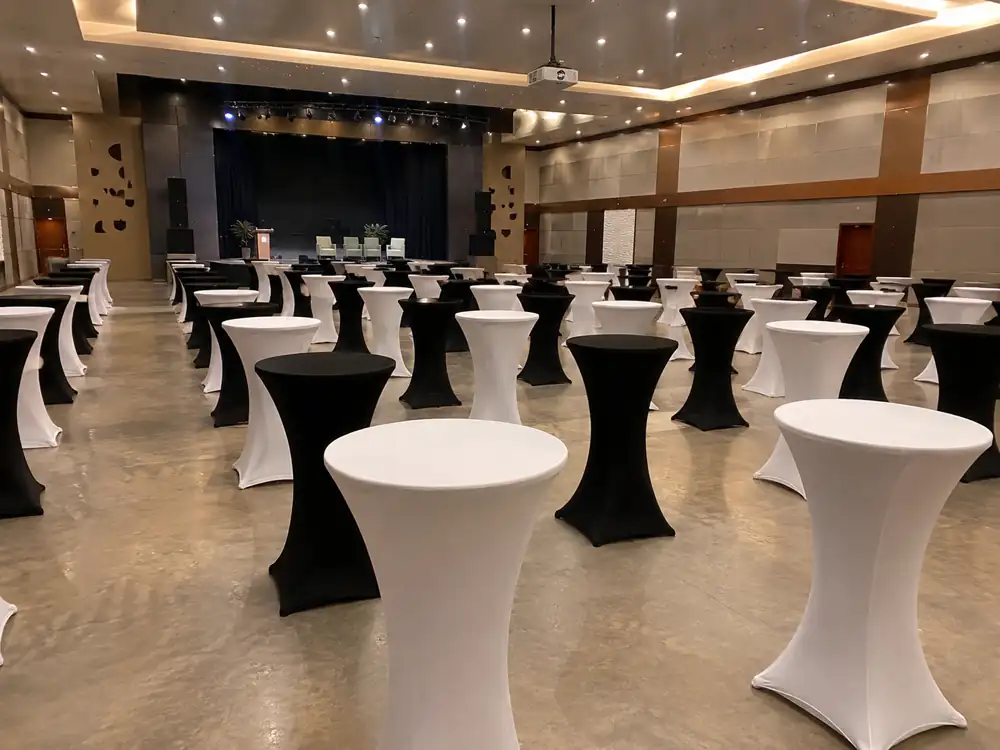 Black and white cocktail tables in a hall facing a small stage