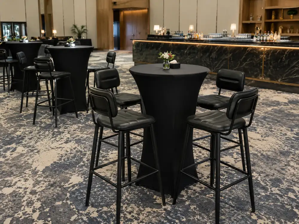 Black cushioned bar stools around cocktail tables in a hotel event space