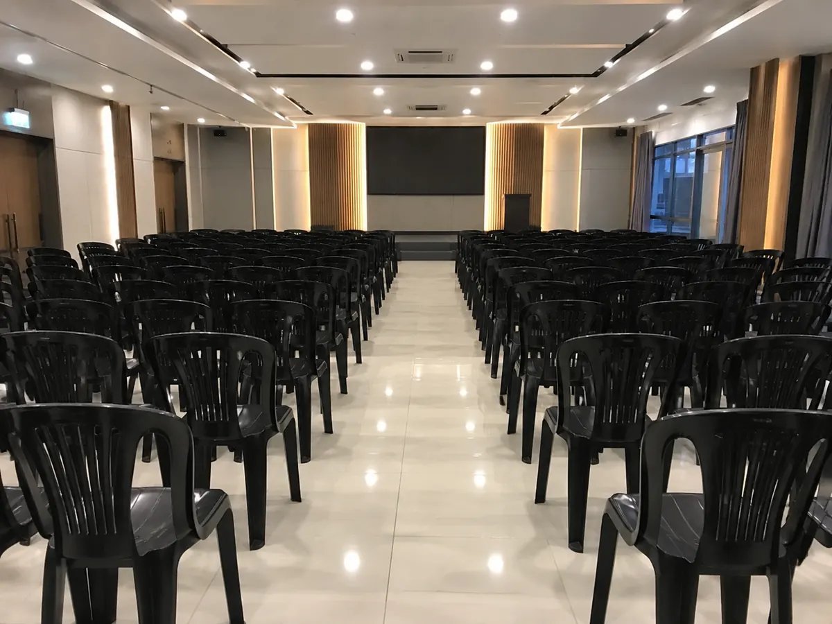 Black plastic chairs arranged in rows in a hall