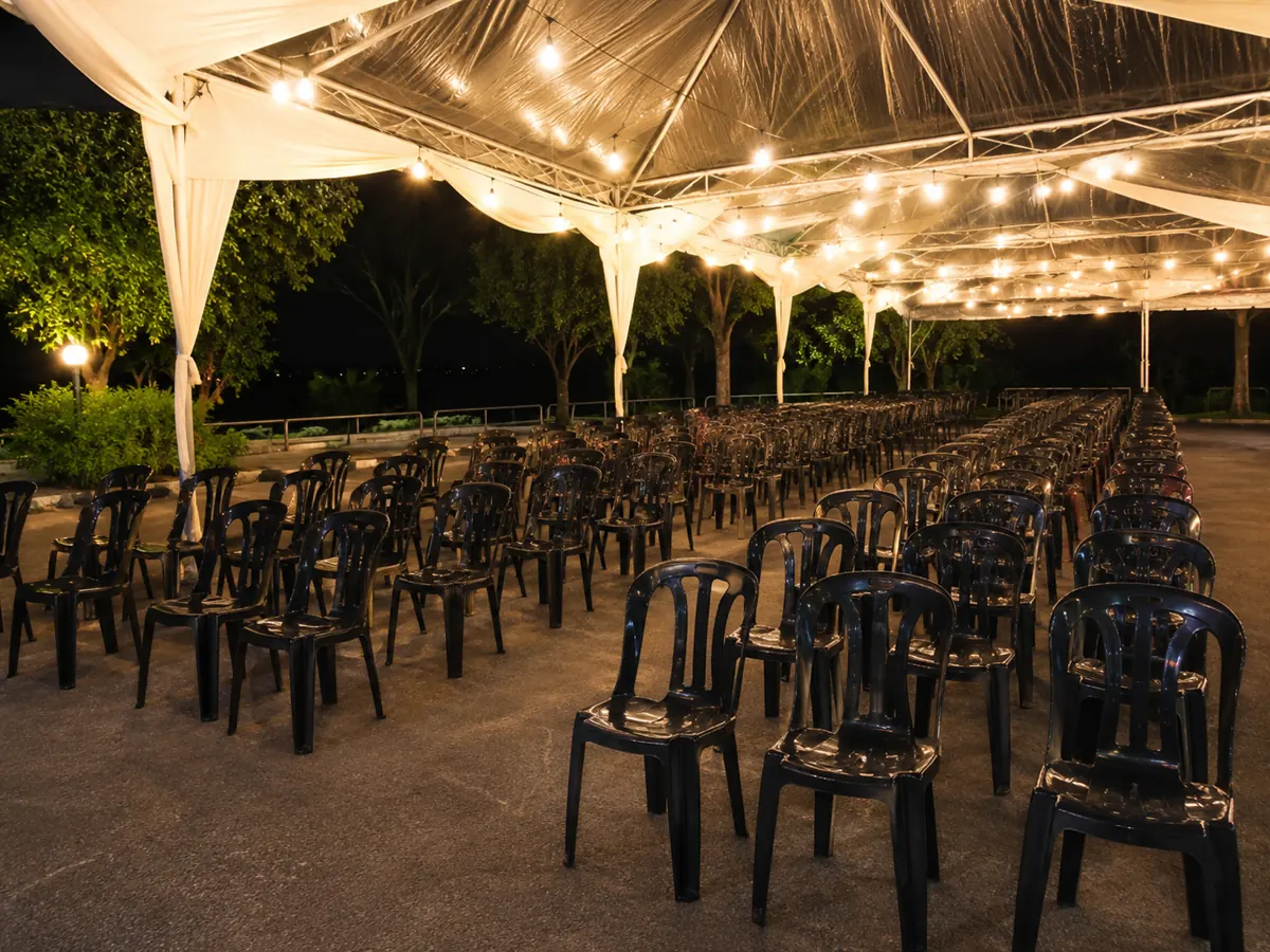 Black plastic chairs arranged under a night canopy with warm lighting
