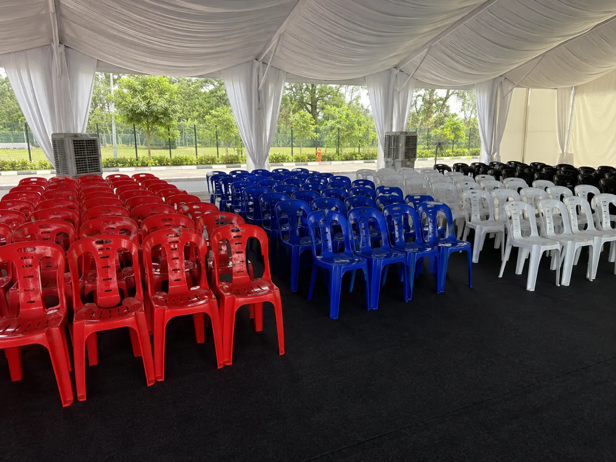 Red blue white and black plastic chairs arranged under a canopy