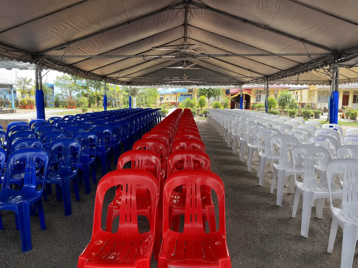 Red blue and white plastic chairs arranged under an outdoor canopy