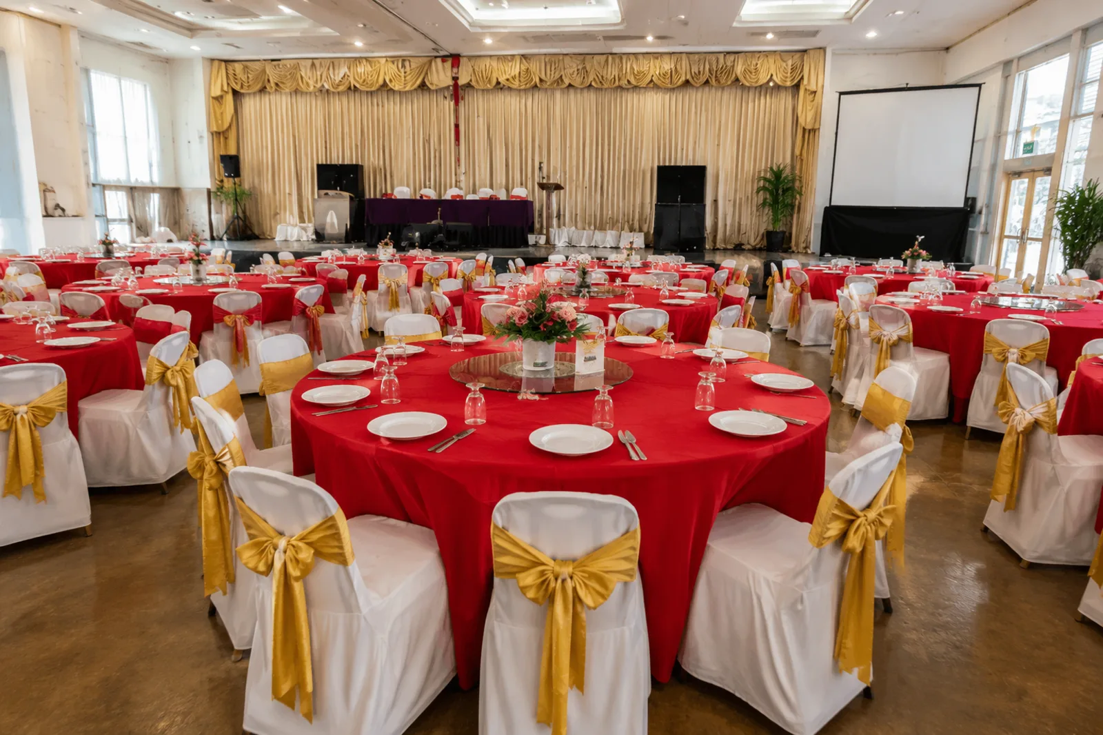 Banquet hall round table setup with red table cloth and covered chairs