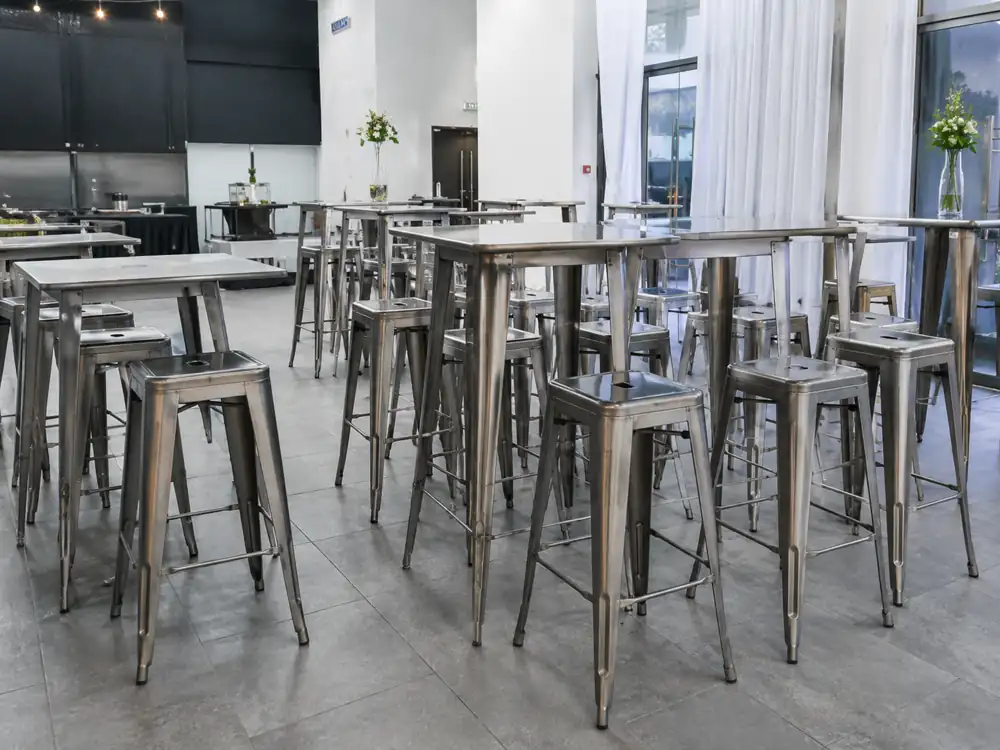 Metal Tolix bar stools with matching high tables for an indoor event setup